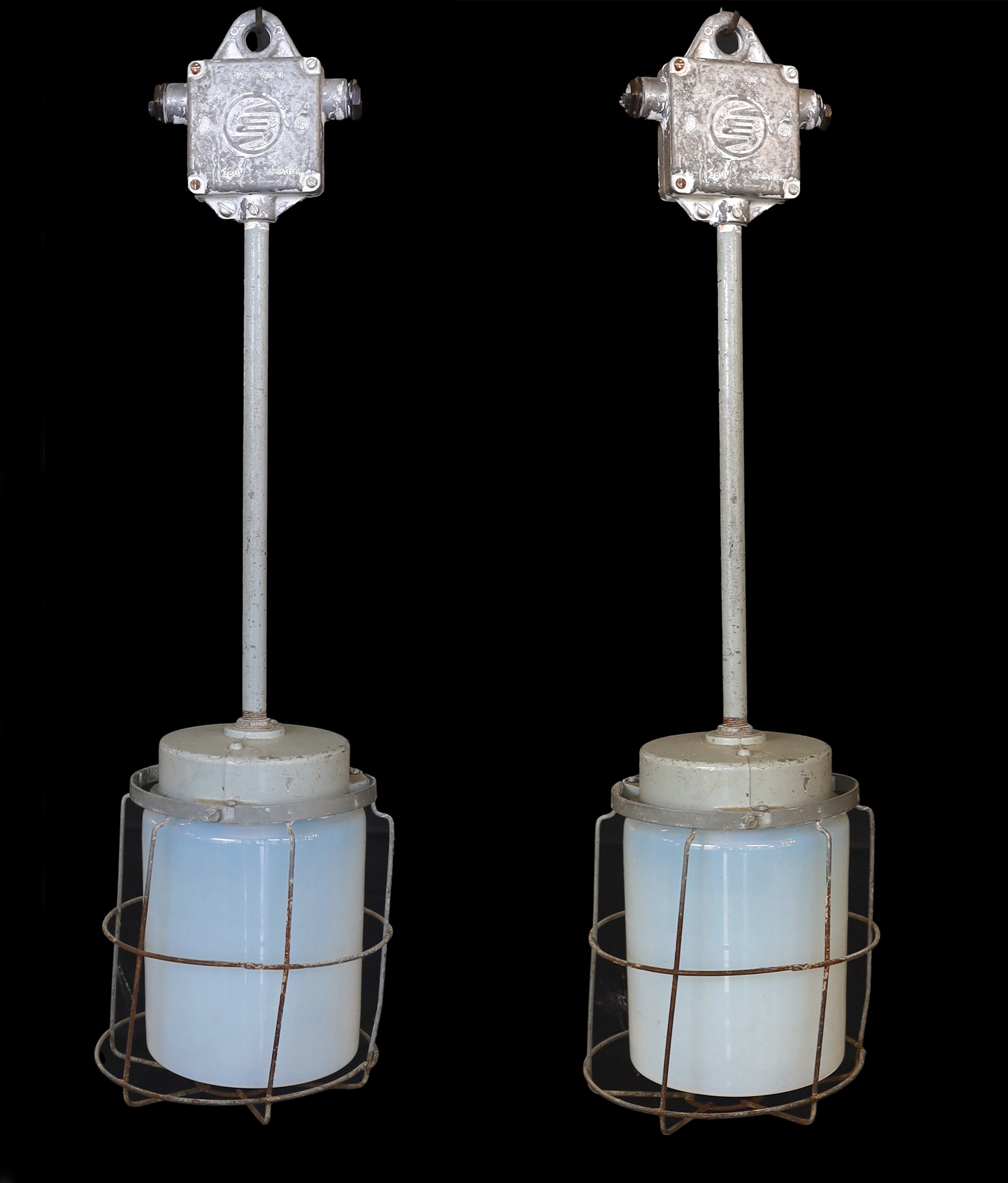 A pair of Czechoslovakian painted alloy industrial ceiling lights with caged Vaseline glass shades, height 74cm. width 21cm